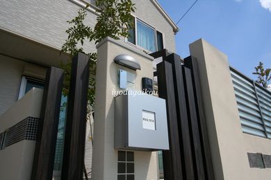 門柱は駐車スペースを考えて、シンプルなユニット式を採用。木目調のアルミ角材でプライバシーも確保です。